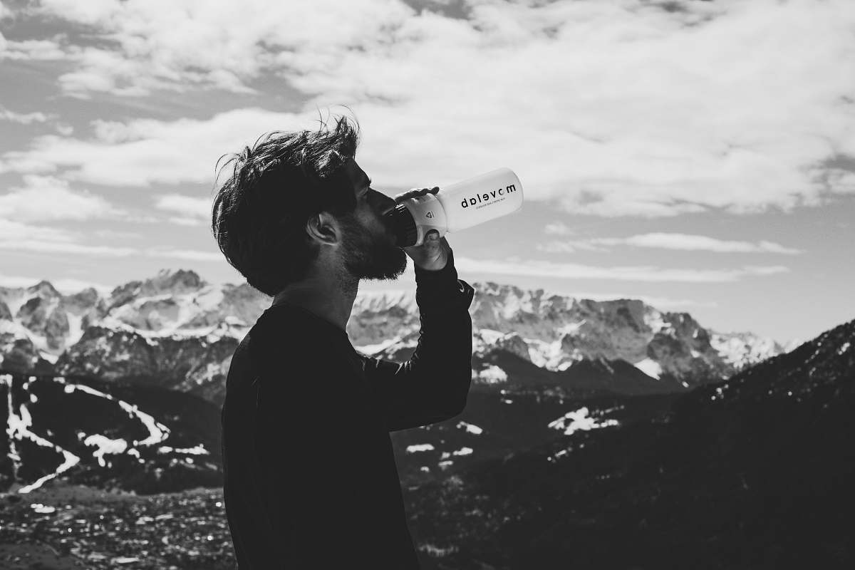 person man drinking water on top of mountian human