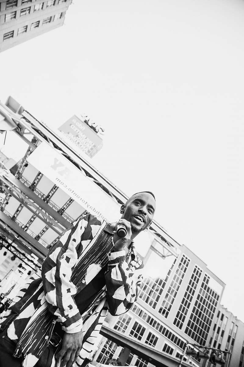 urban man holding microphone while standing outdoor grayscale photography toronto