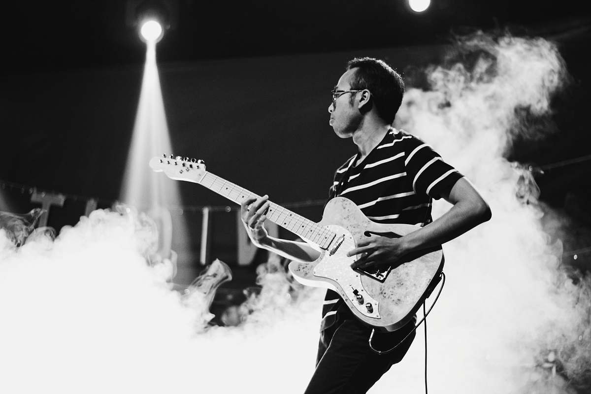 human man playing guitar on stage with smoke person