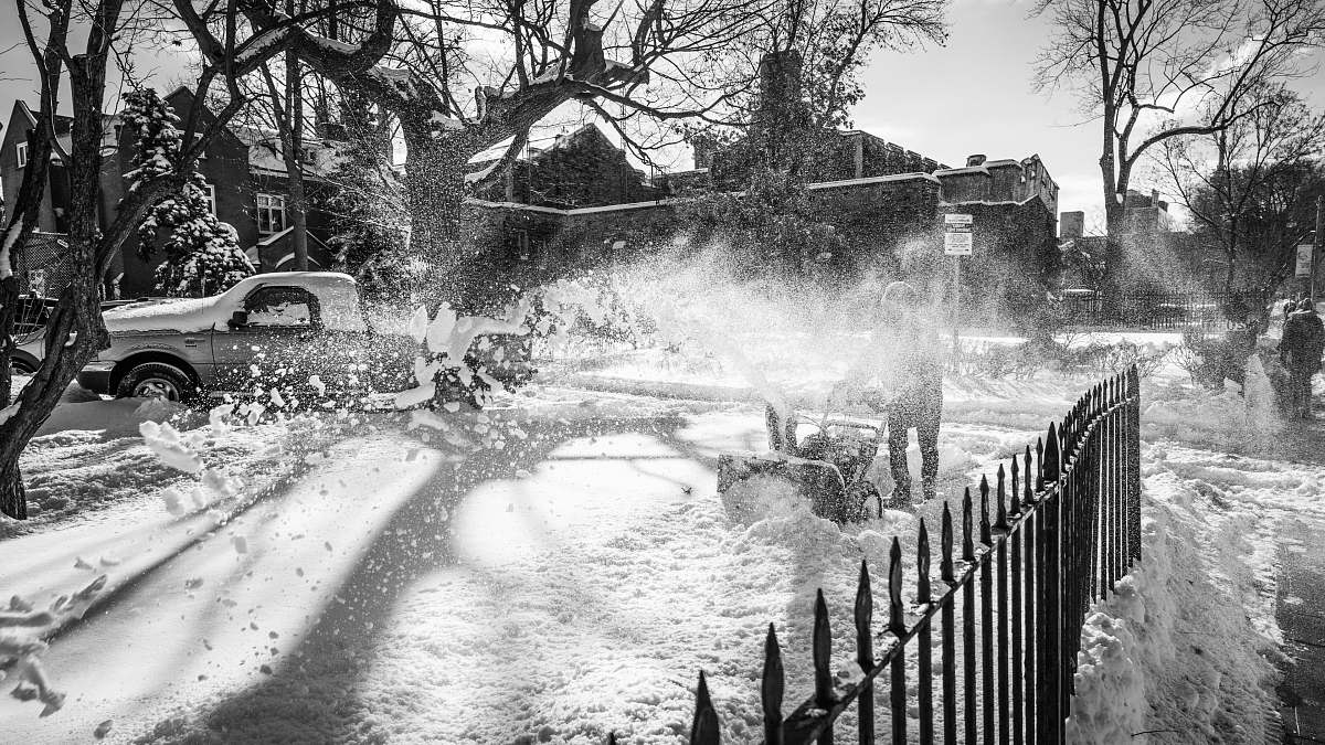 nature man pushing snowblower to clear up snow at the driveway outdoors