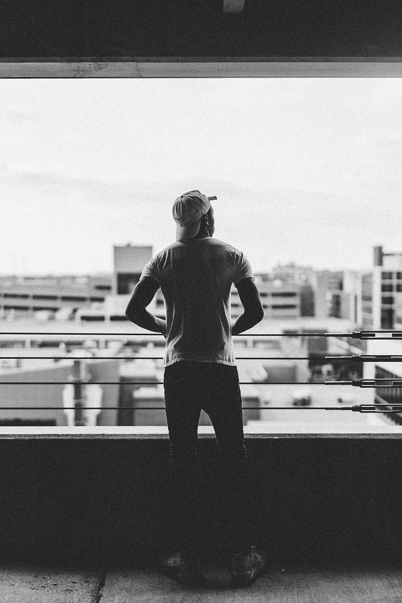 shorts man standing beside handrail of a building apparel