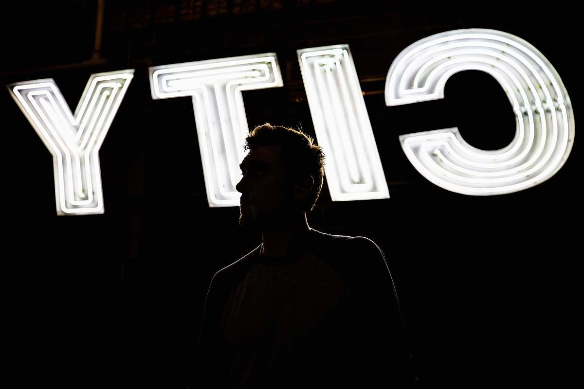 human man standing in front of CITY light signage portrait
