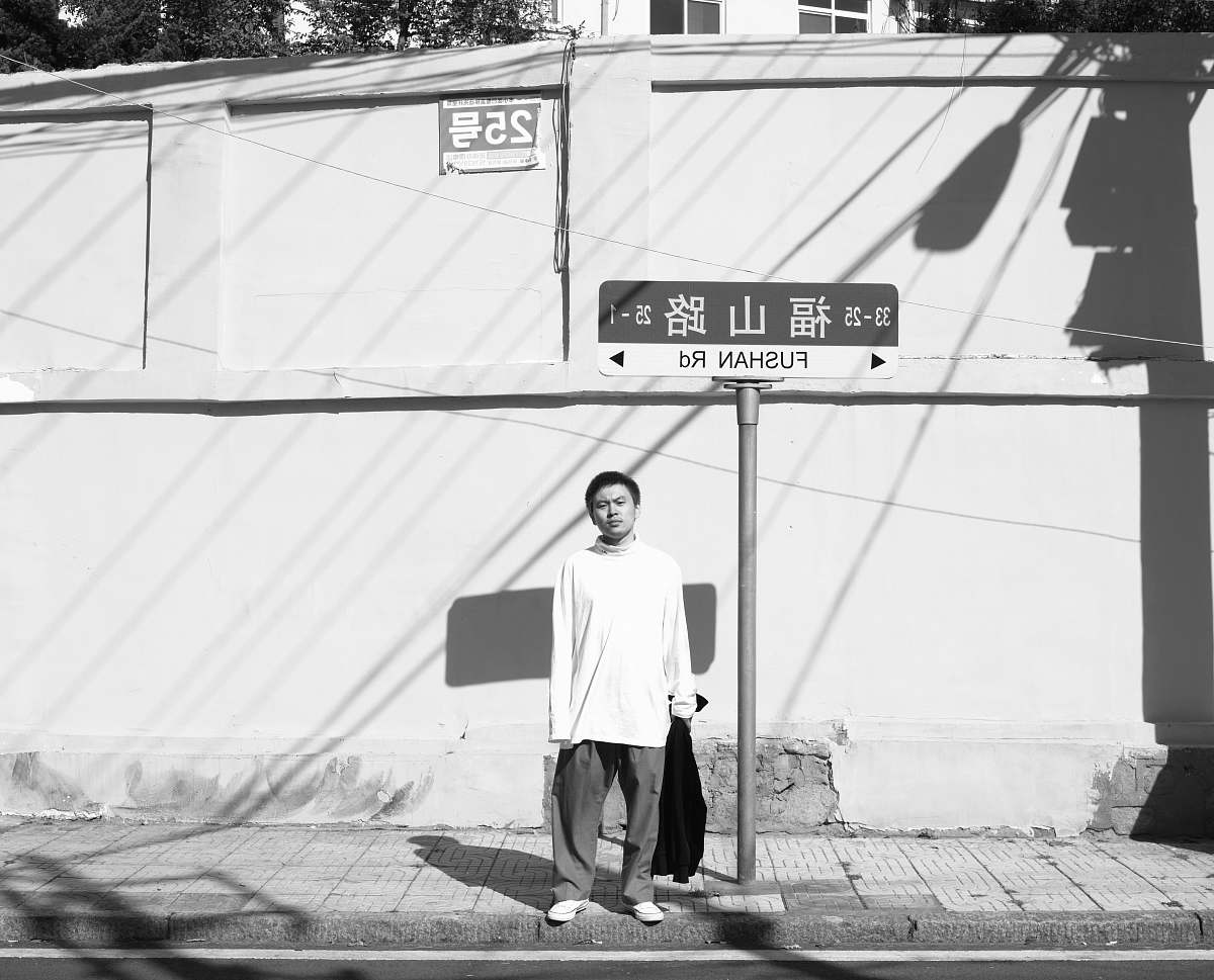 apparel man standing near street post grayscale photo clothing