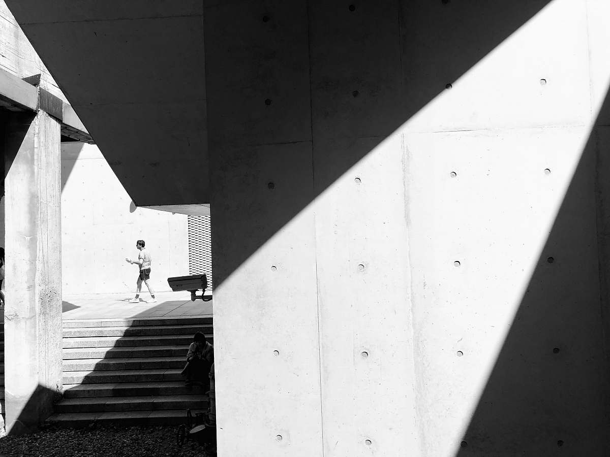 banister man walking past stairs in sidewalk grayscale photo handrail