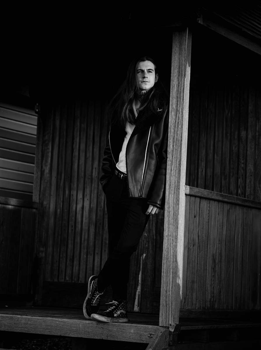 apparel man wearing jacket leaning on post clothing