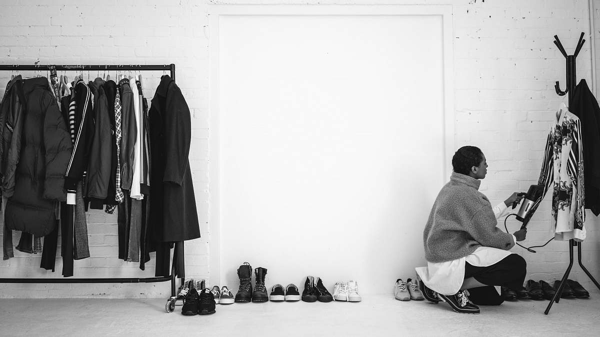 person person ducking in front of black steel coat rack human