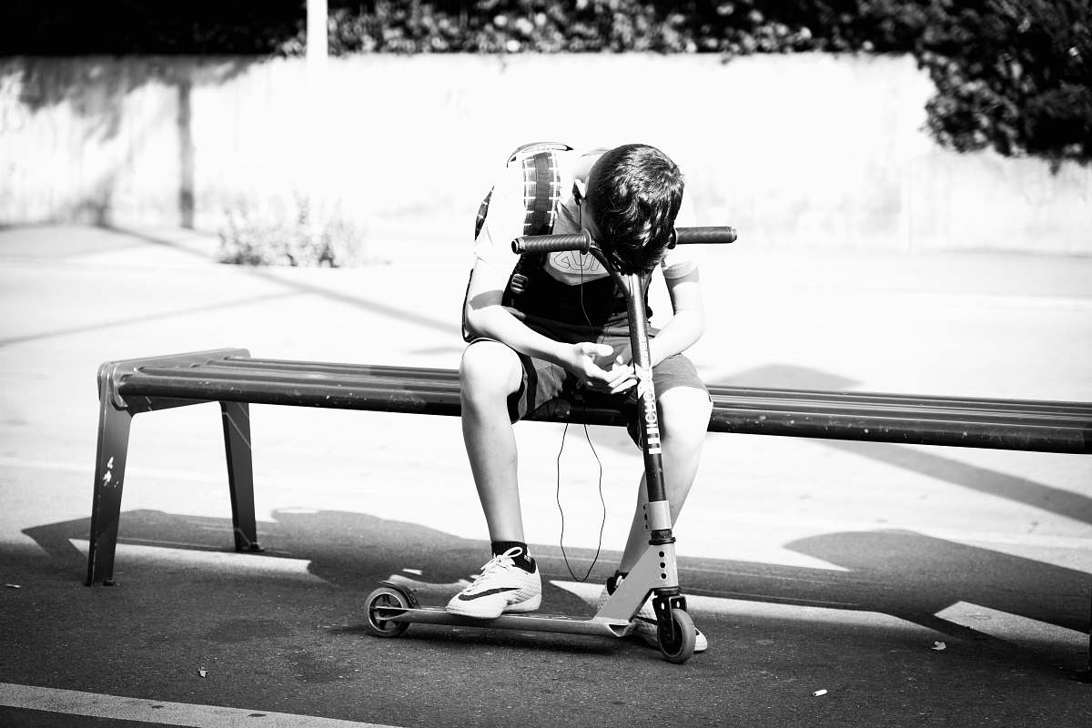 human person leaning on black kick scooter person