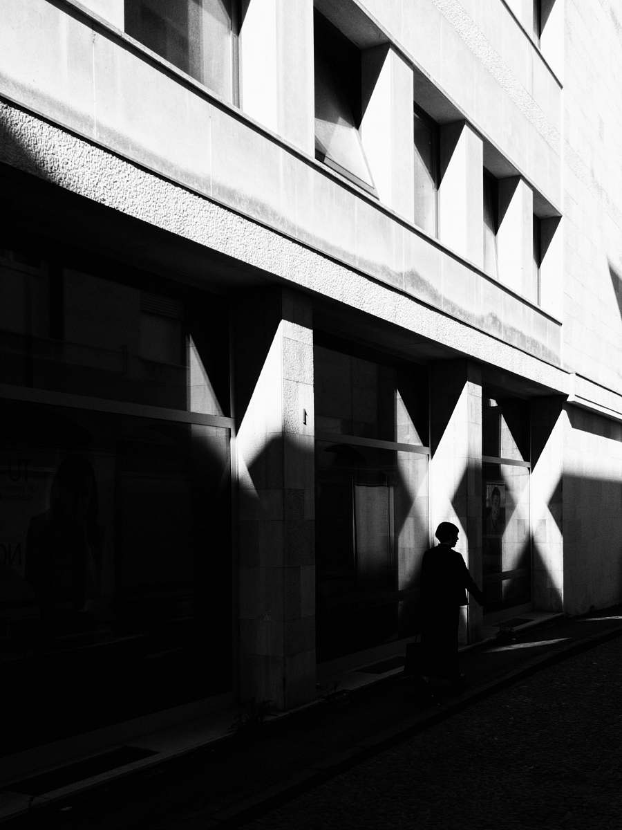 silhouette person walking near building street photography