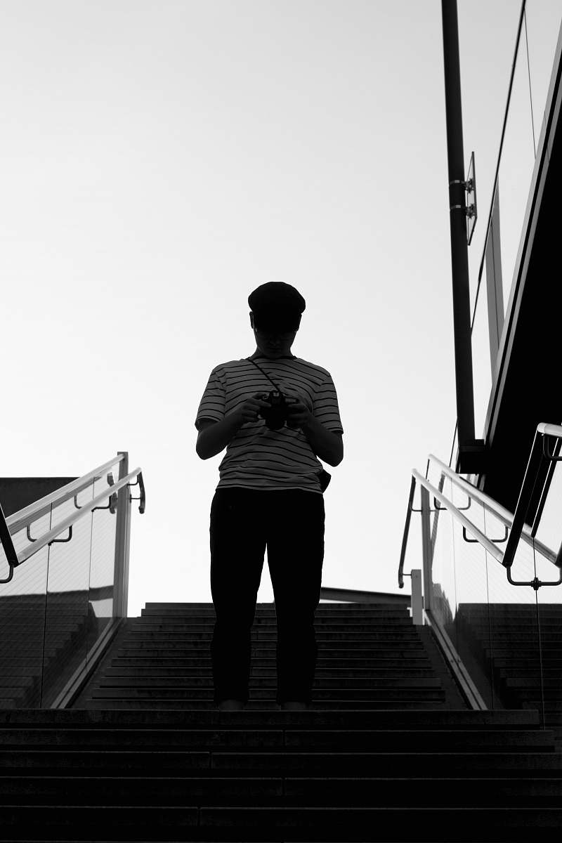 banister person wearing black and white stripe shirt standing on stair handrail