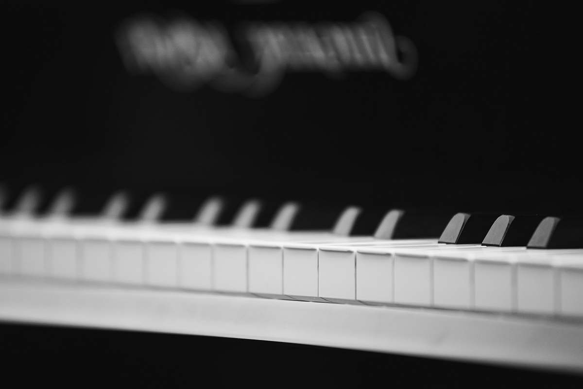grey photo of white and black piano keyboard