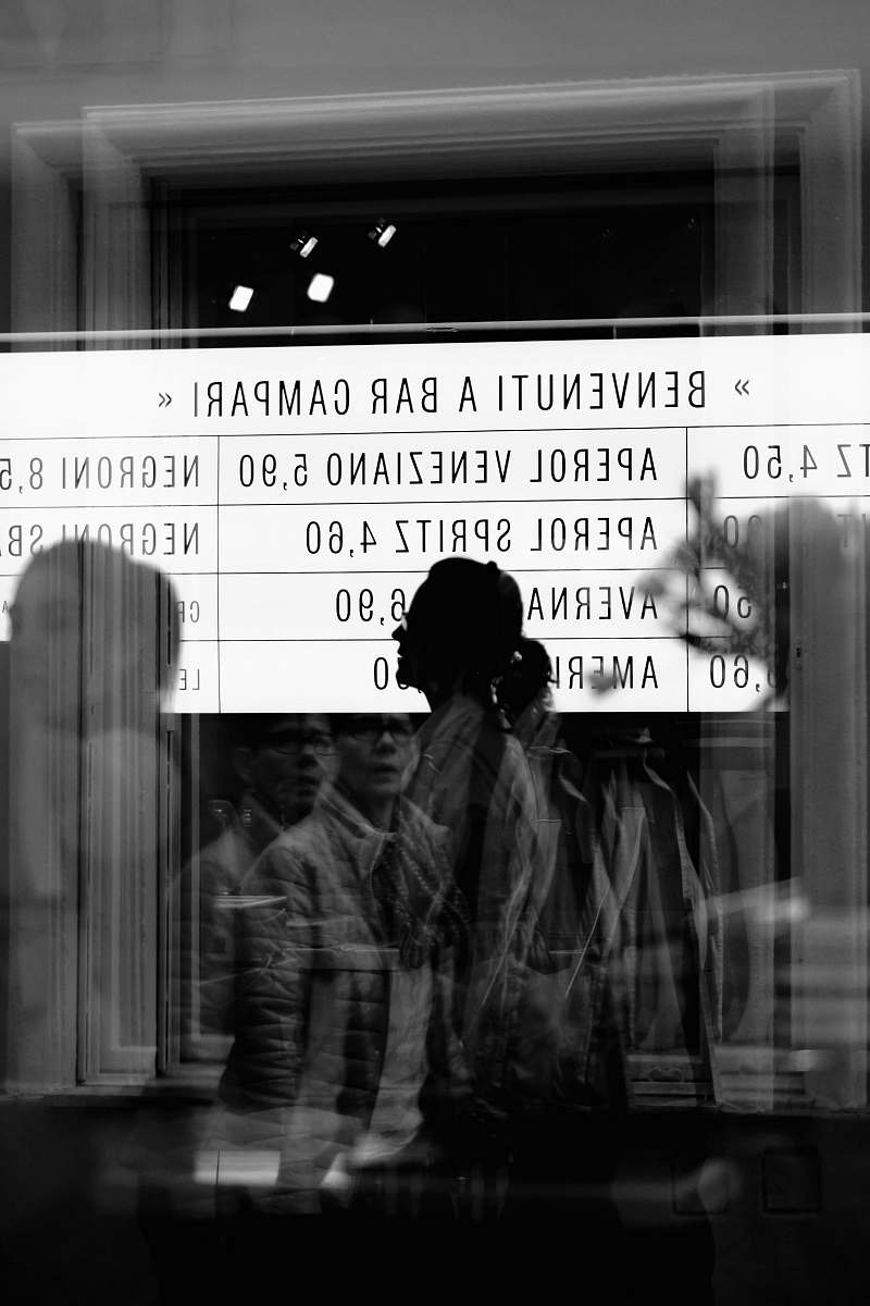person reflection of people from glass panel walking and passing signage in grayscale photography human
