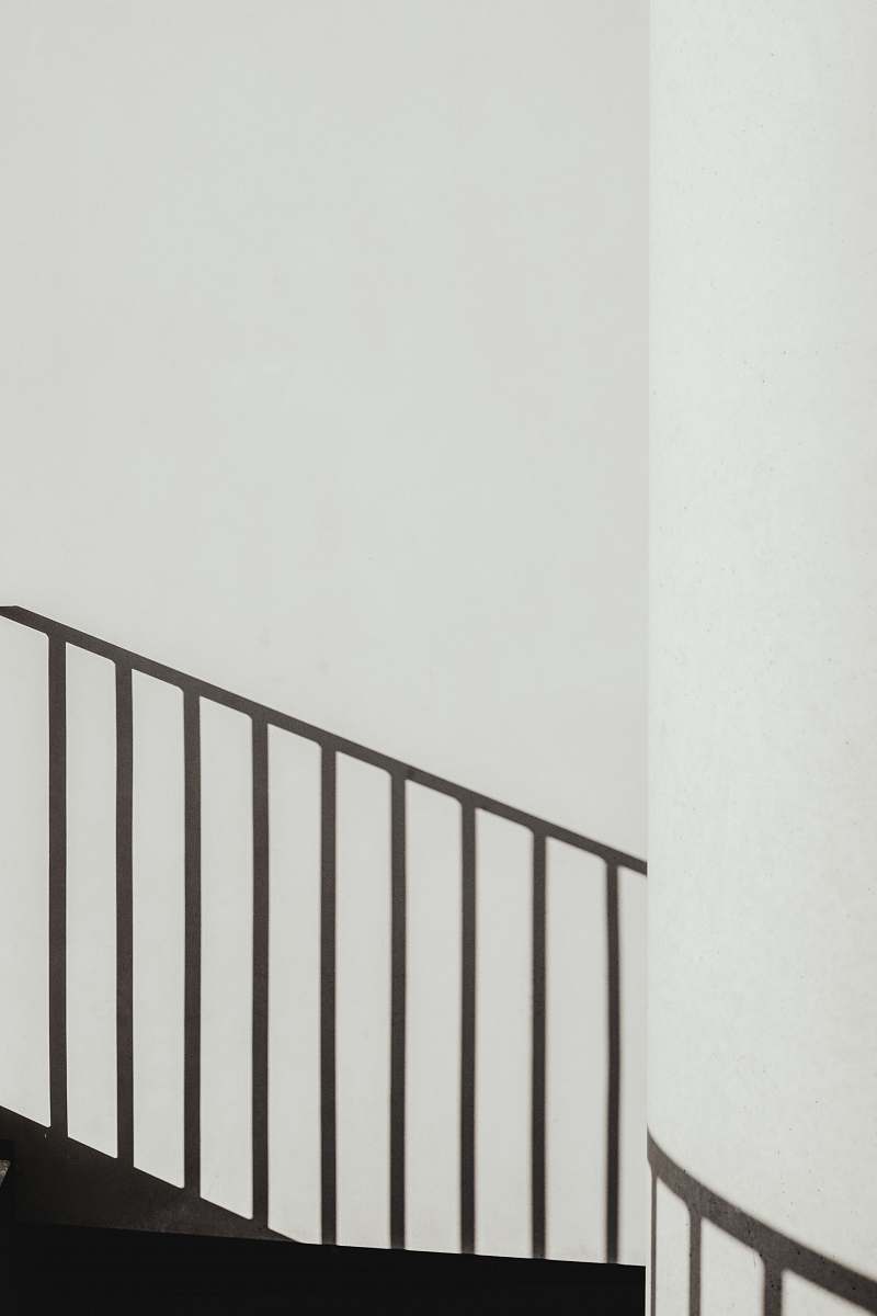 grey shadow of stair rails on white painted wall shadow