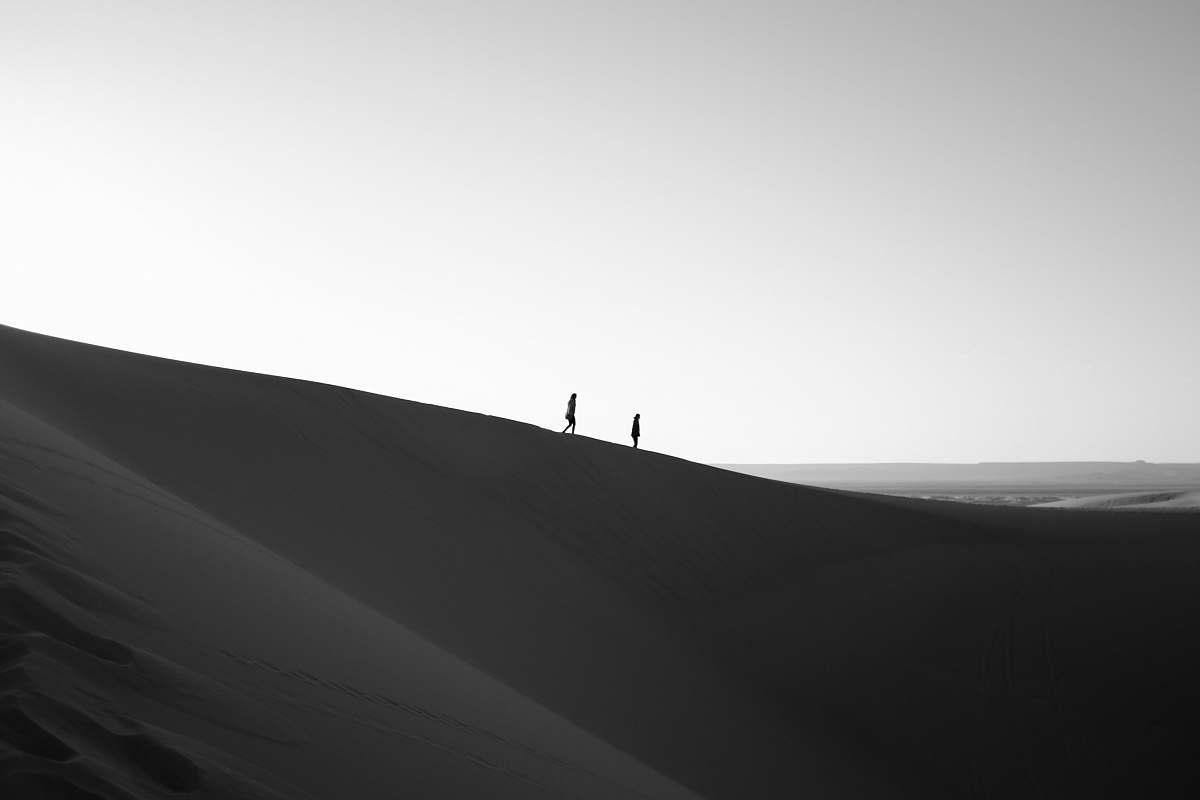 dune silhouette of two person walking on dessert desert