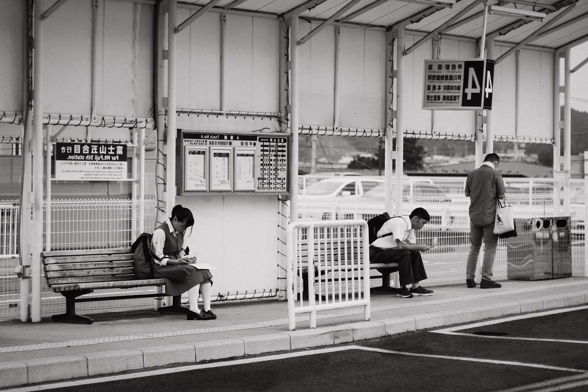 bench students sitting on bench near bus stop furniture