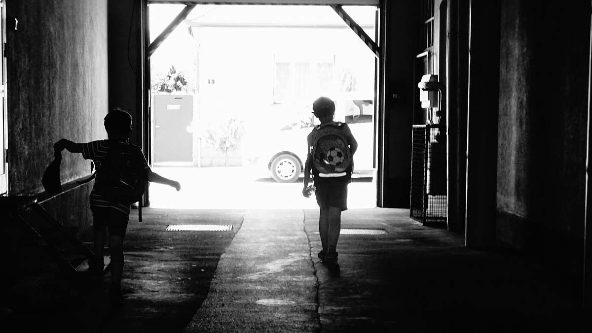 human two boys walking in corridor of a building grayscale photo person