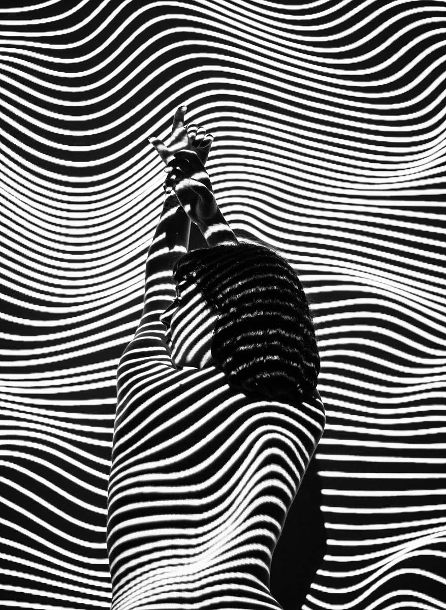 white woman raising both arms with stripe light color black