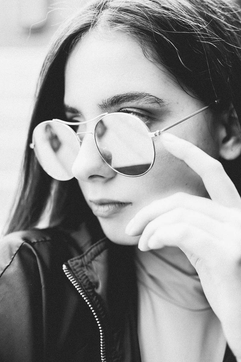 A fashionable woman confidently sports a pair of stylish sunglasses paired with a chic jacket, embodying modern urban style. This image captures the essence of contemporary fashion and self-expression, perfect for use in lifestyle blogs, fashion magazines, or advertising campaigns targeting trendy audiences. The vibrant setting enhances the aesthetic, making it an ideal choice for various creative projects.