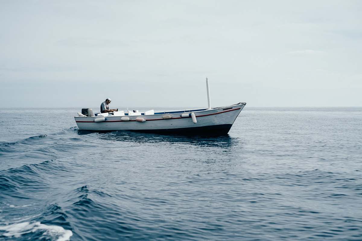 dinghy man sitting on boar in ocean ocean