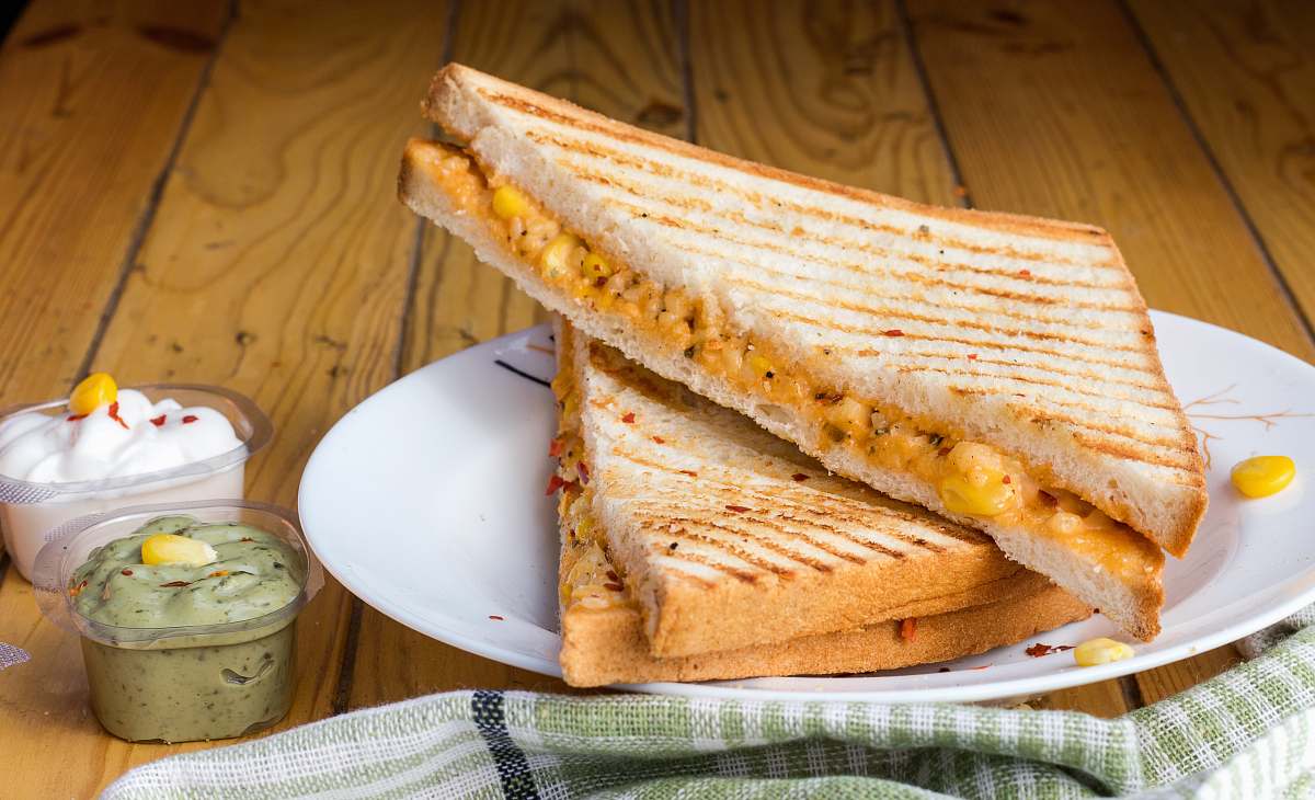 sandwich bread with cheese fillings on white ceramic plate corn