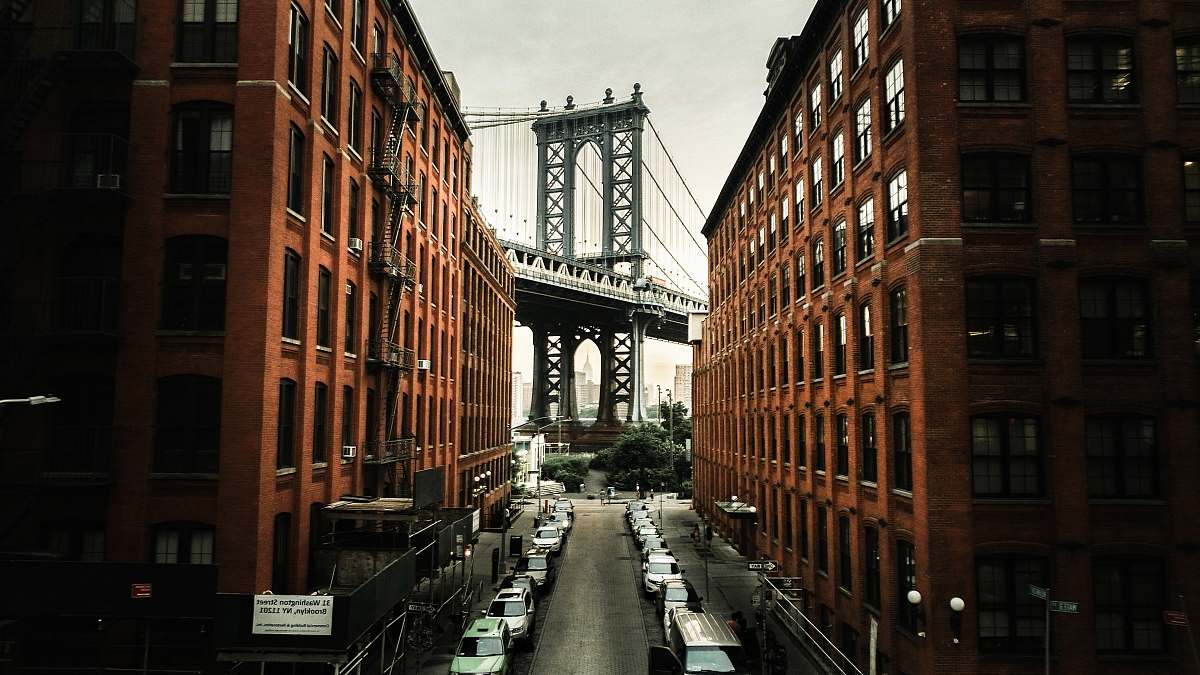 city cars parked on both sides of street near bridge dumbo
