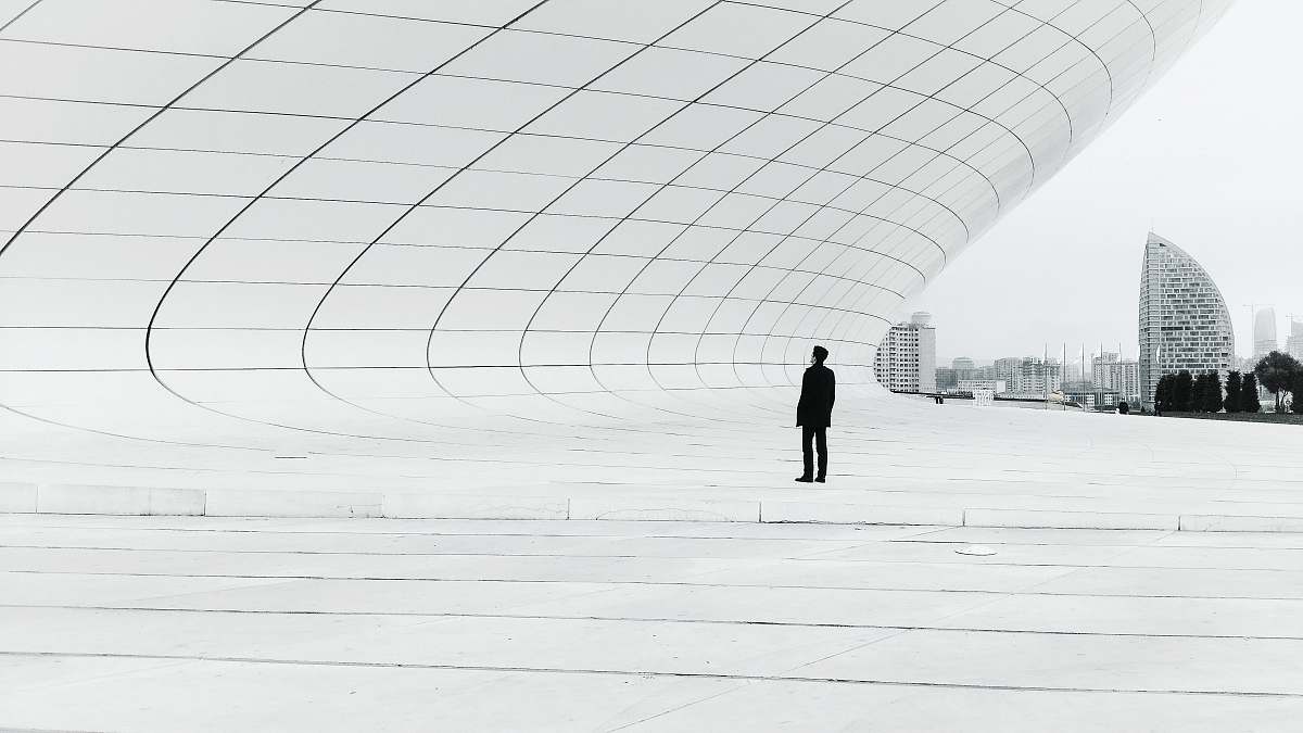 grey person standing in a middle of white plate field architecture