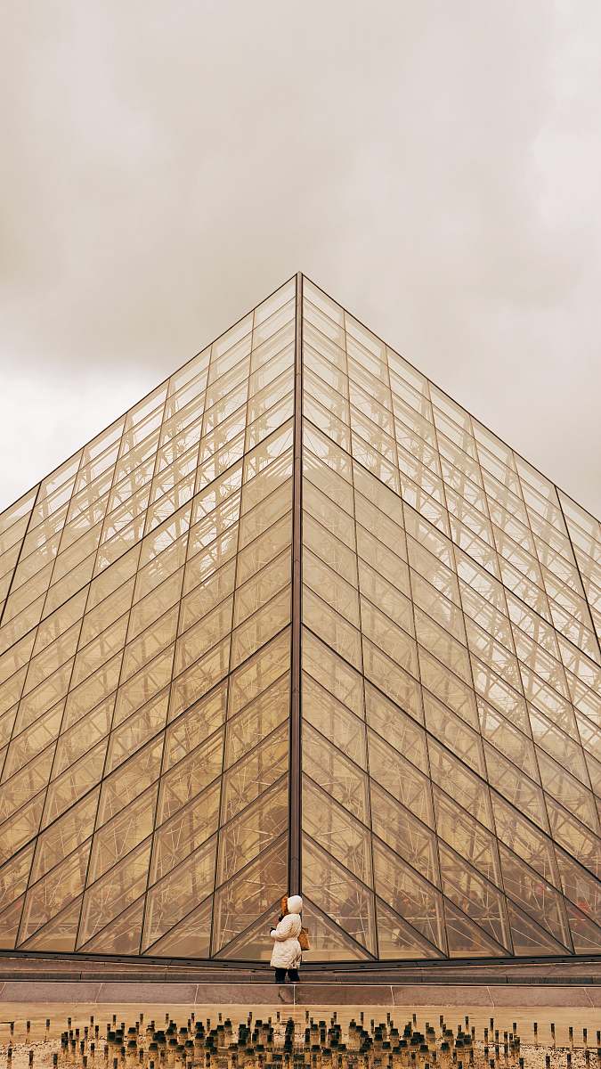 paris person standing in front of brown glass building during daytime france