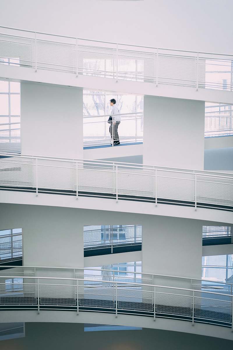 grey person walking on stairs inside building during daytime balcony