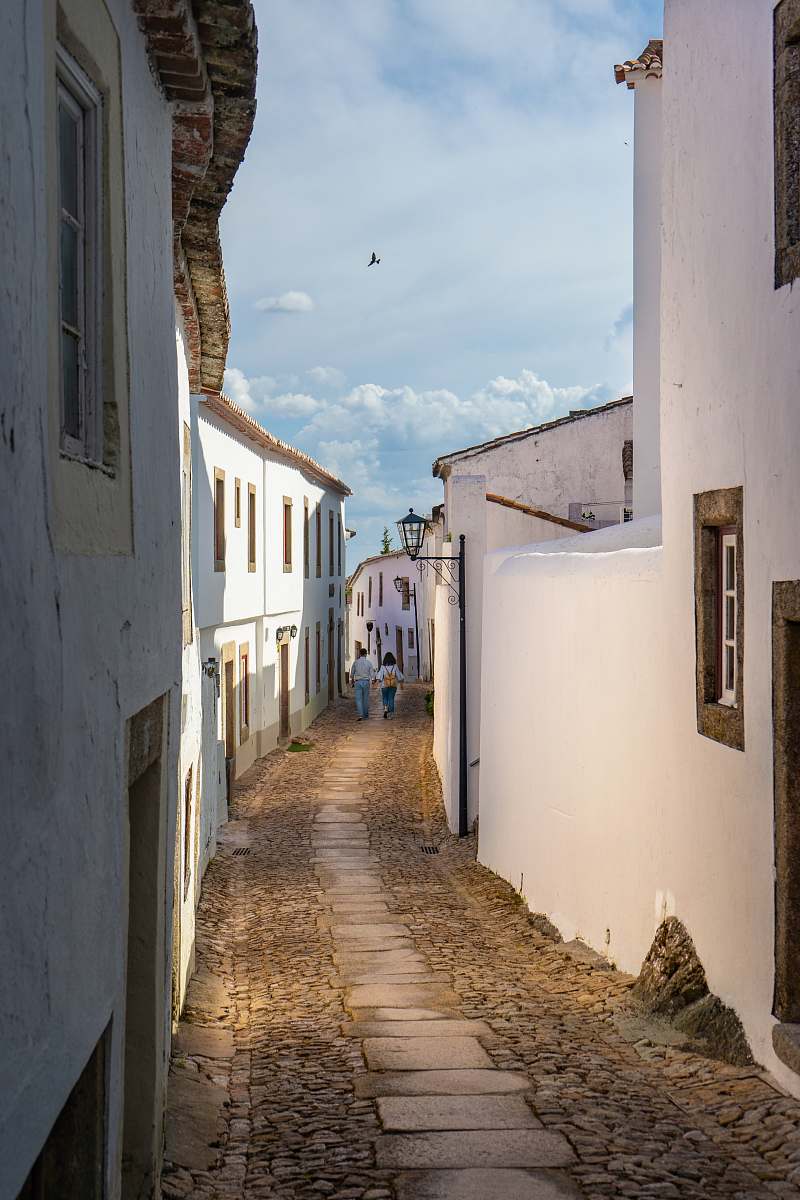 street two person walking concrete pathway between houses city