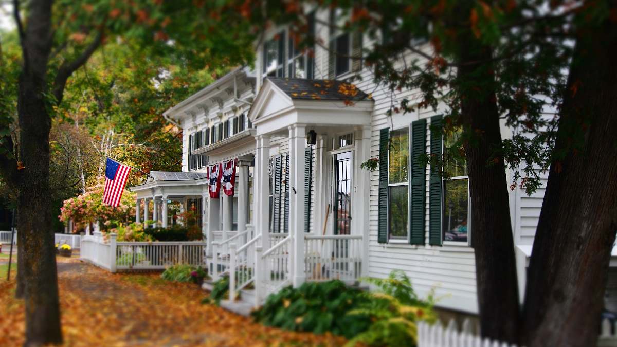 house white and gray wooden house with US flag flora
