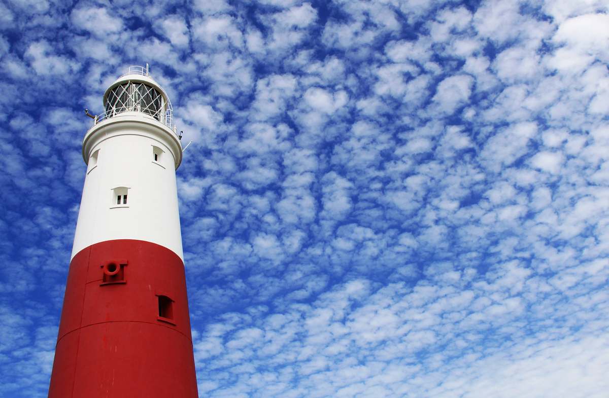 beacon white and red lighthouse under cloudy sky blue