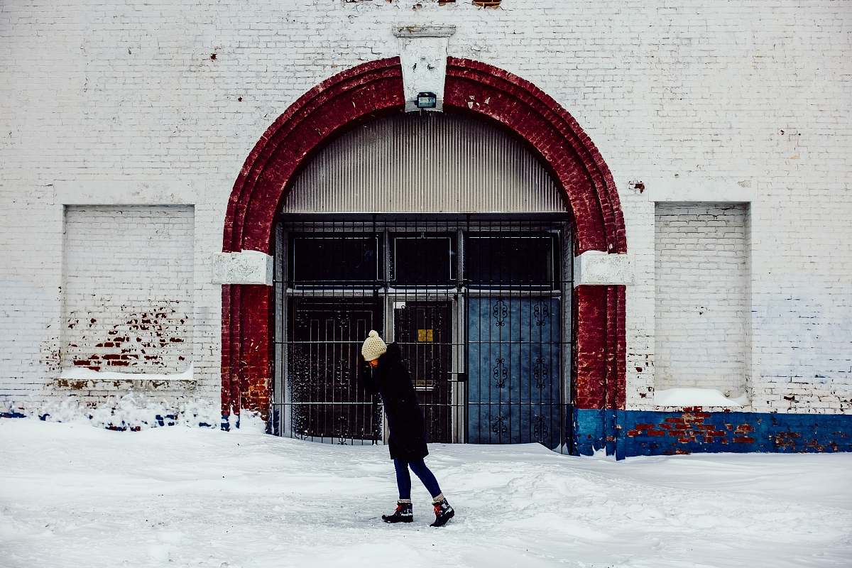 person woman standing in front of white concrete building snow