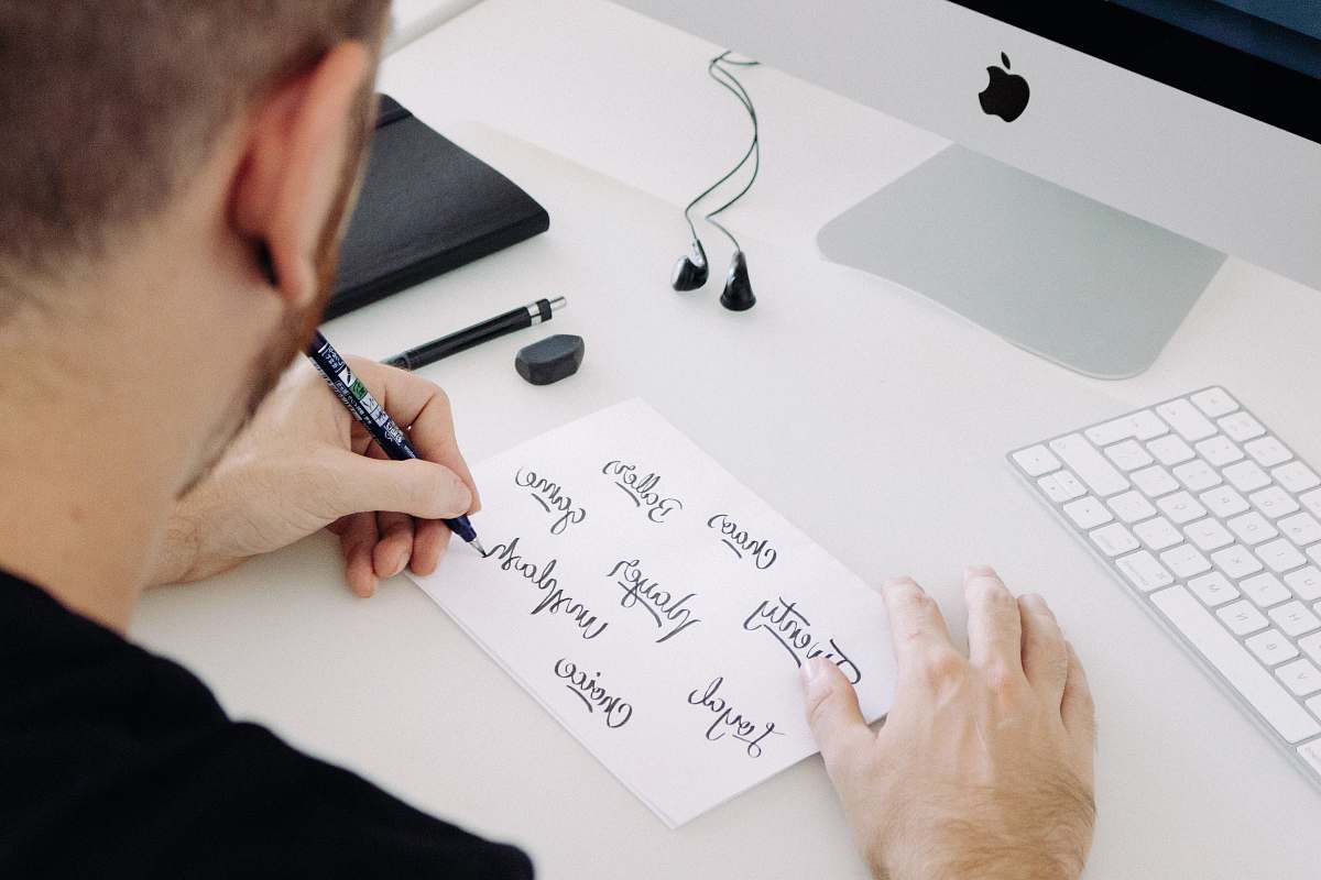 faro person writing on white printer paper in front of silver iMac portugal