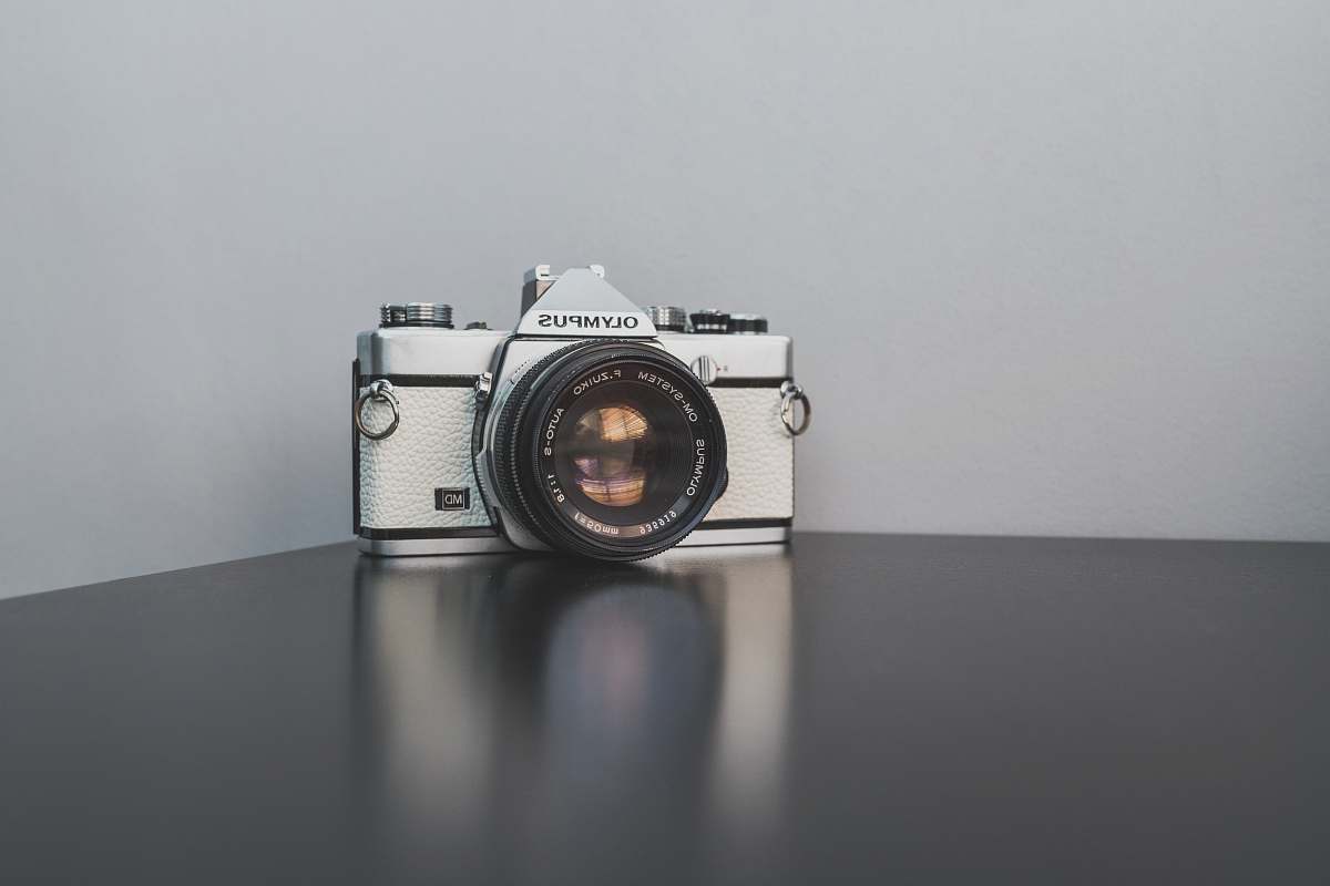 grey gray and black Olympus SLR camera on black surface olympus