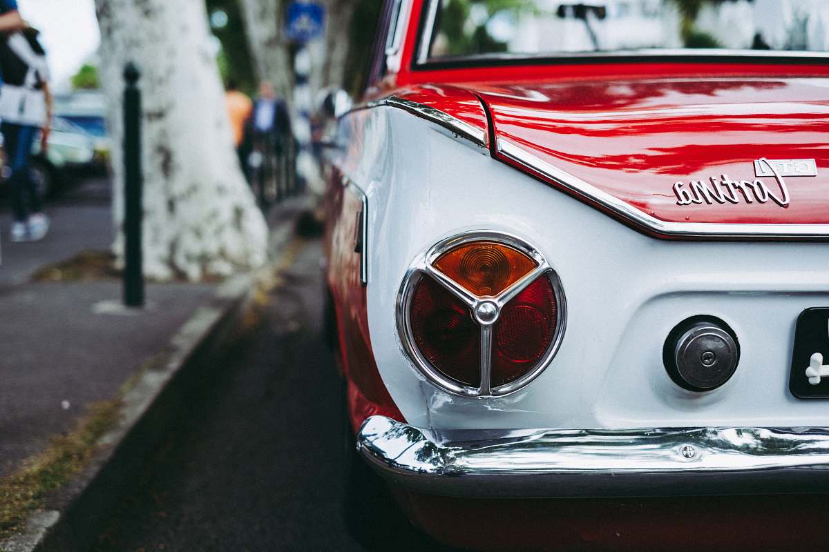automobile red and white Cortina car parked beside tree vehicle