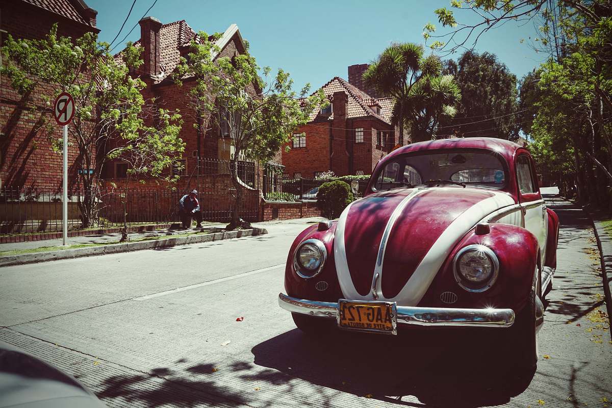 colombia red and white Volkswagen Beetle on road near brown house vehicle