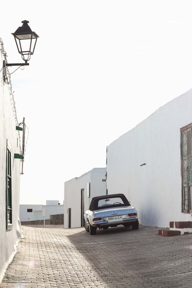 automobile silver car parked beside white building transportation