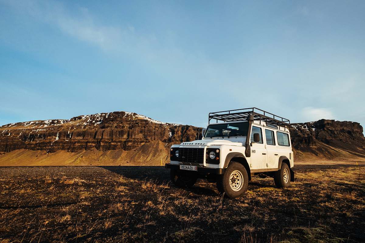 vehicle white Jeep Wrangler near brown mountain at daytime iceland