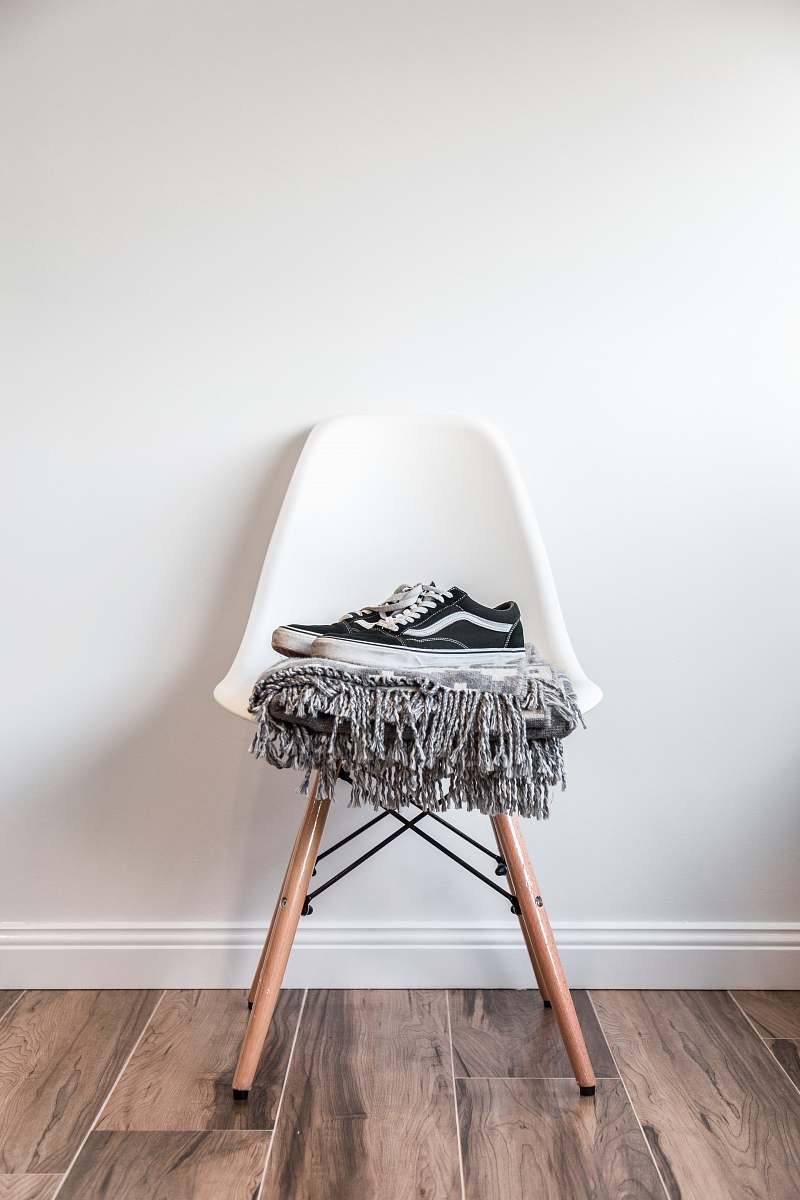 interior pair of black low-top Vans sneakers on white chair furniture