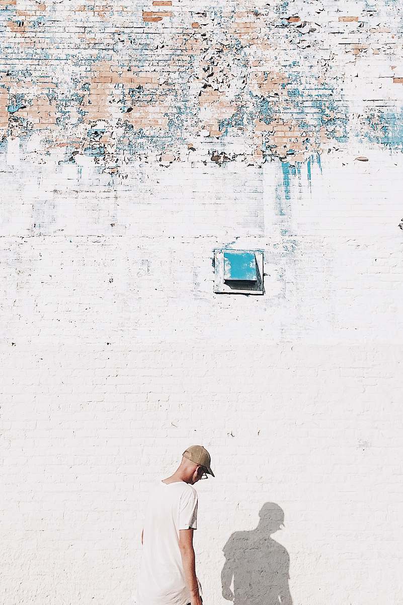 person man standing facing white brick wall human