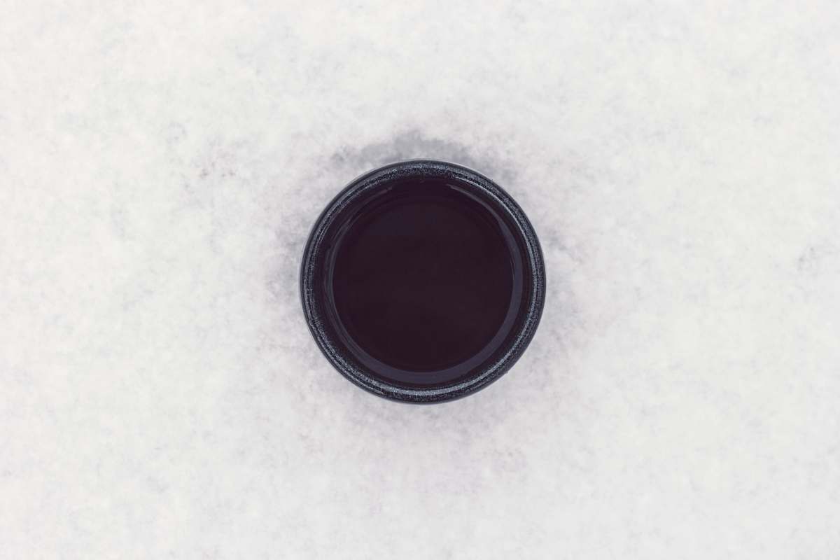 cold round black container on top of white surface drink