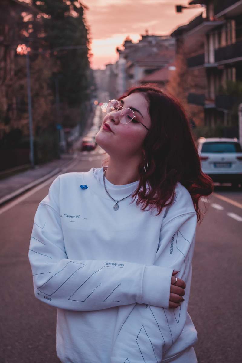 apparel woman standing on road near vehicle and buildings human