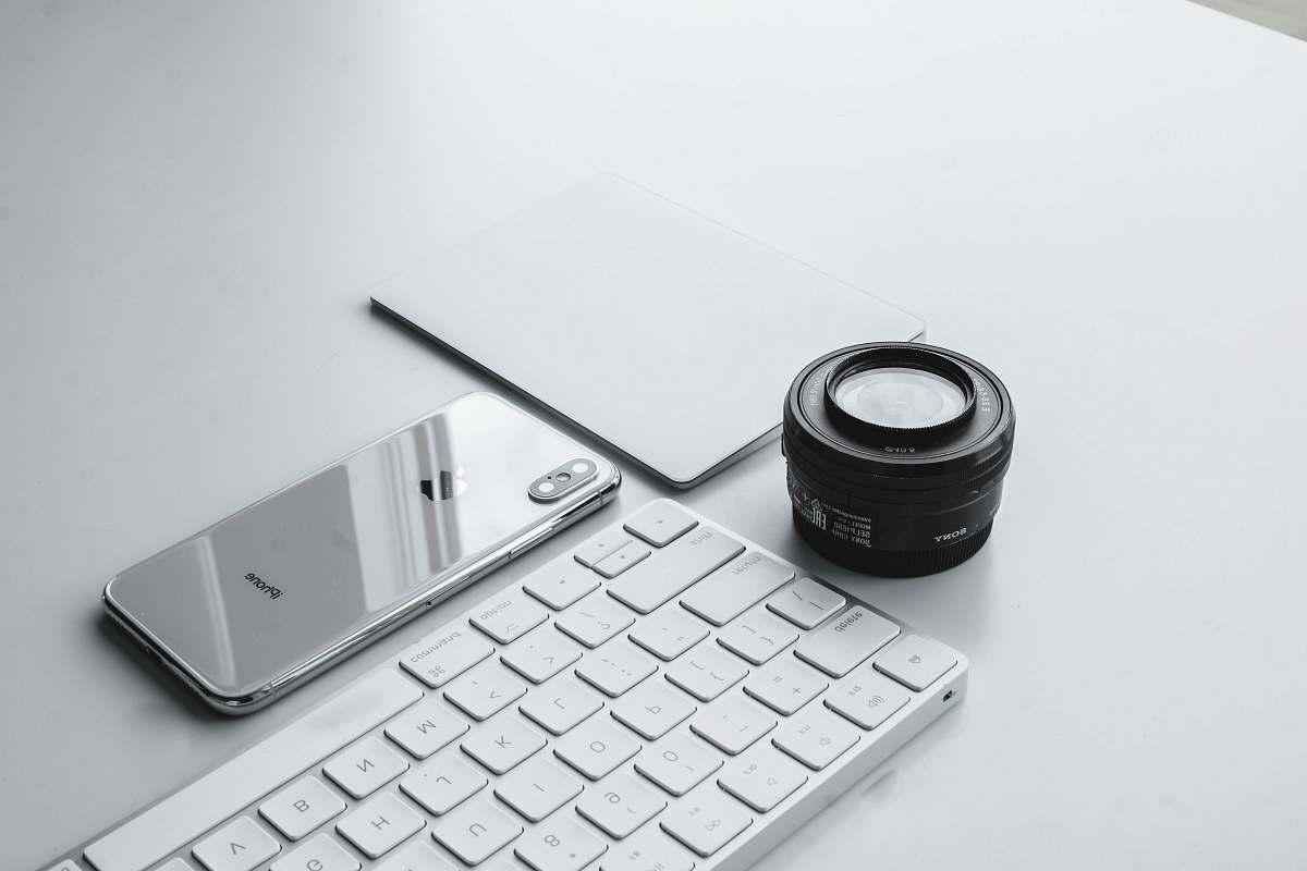 keyboard silver iPhone X beside camera lens and Apple Keyboard shade