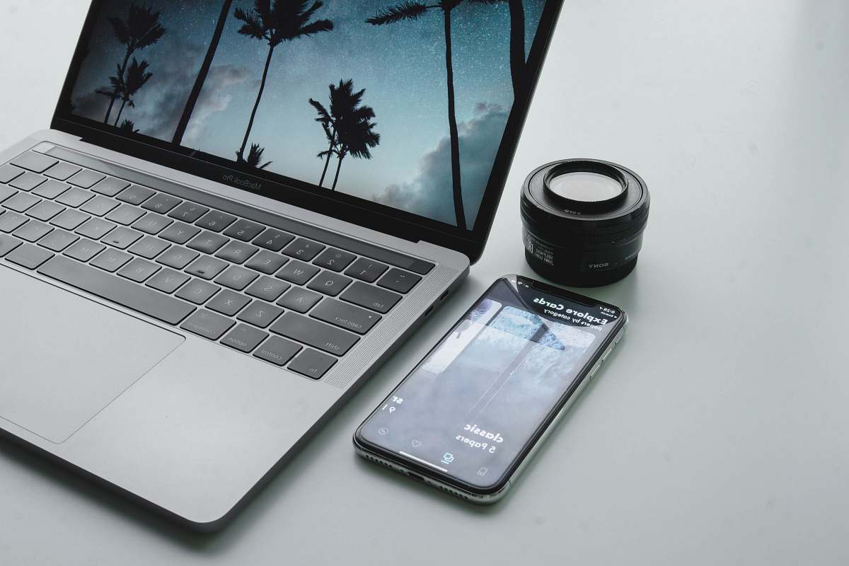 shade turned-on MacBook Pro beside black smartphone on gray surface tree