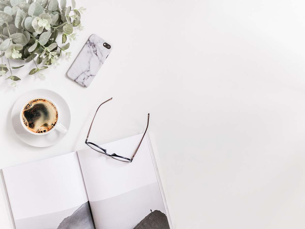 phone clear eyeglasses next to white coffee cup cell phone
