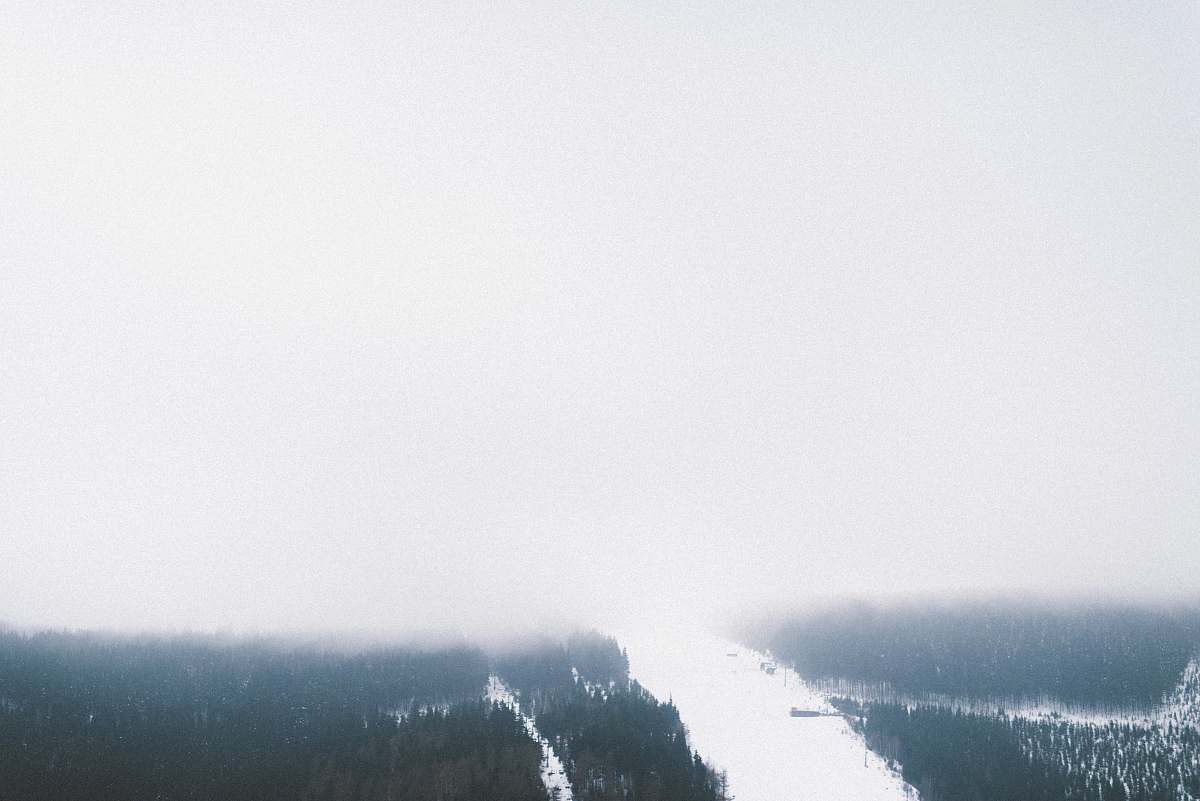 weather A high view of a snowy wooded slope shrouded in heavy mist in Špindlerův Mlýn forest