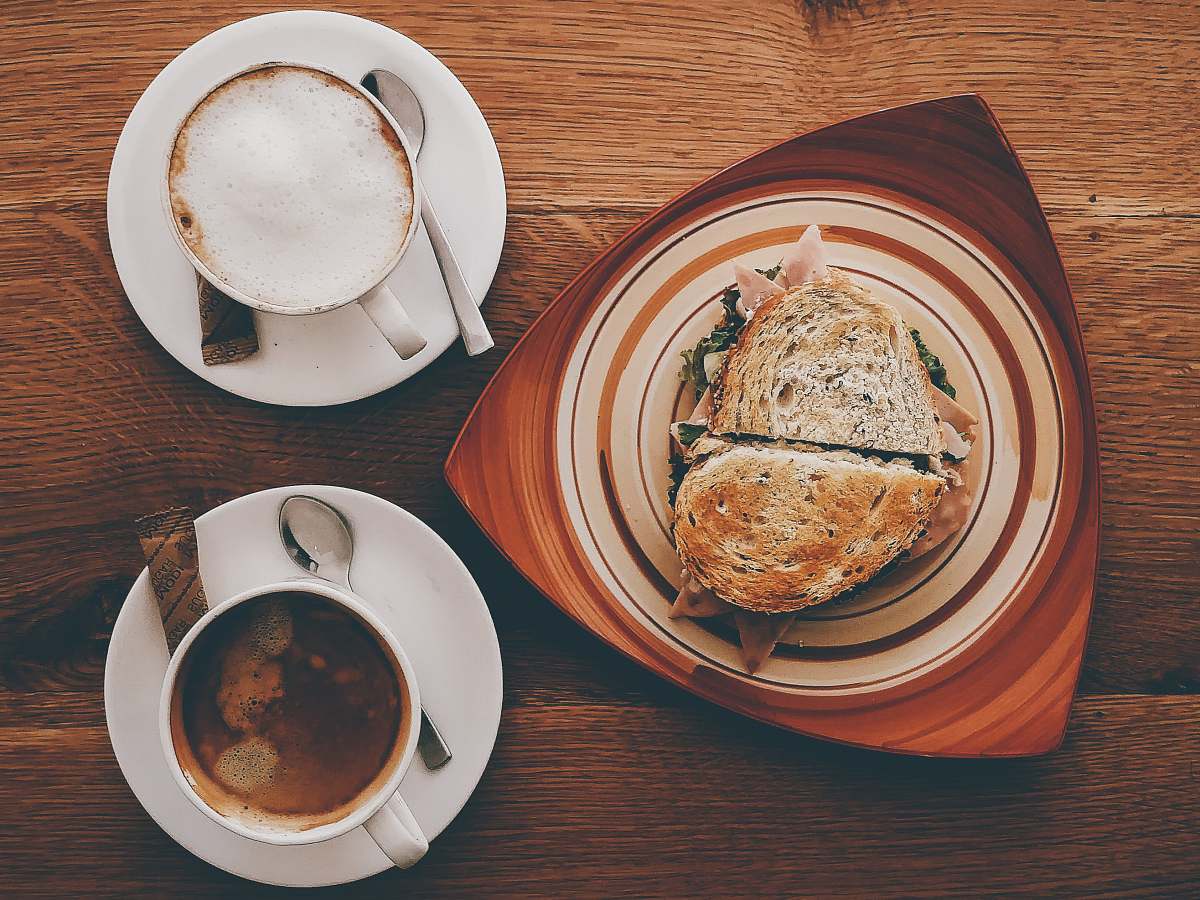meal ham sandwich on plate near cappuccino on mug and coffee breakfast