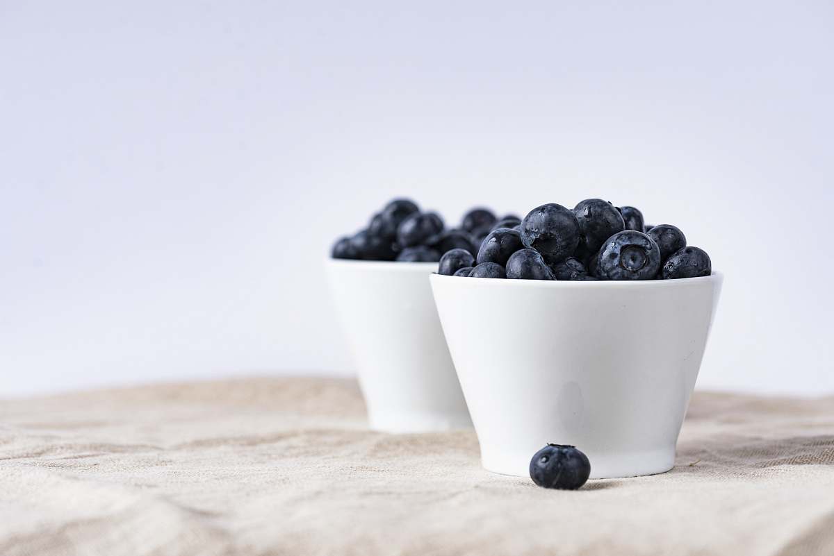 fruit two white ceramic cup filled with blueberries fruit place on brown textile blueberry