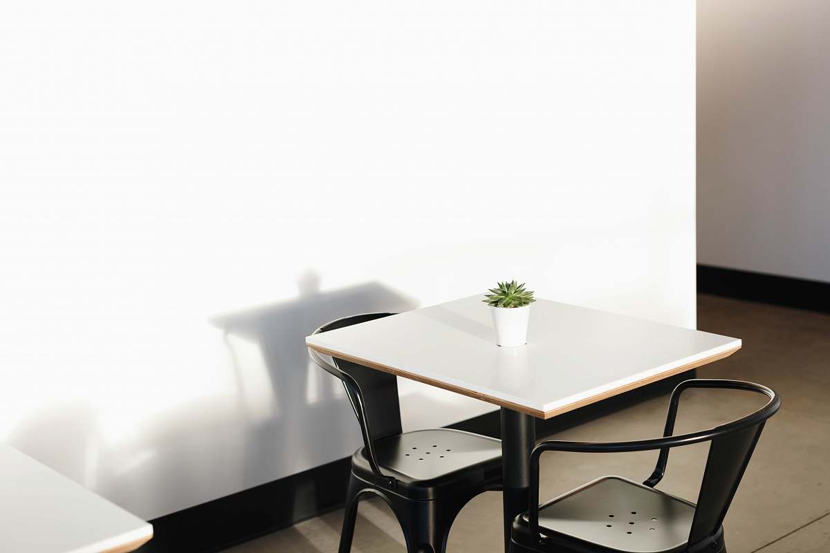table square white wooden table with two black metal chairs dining table