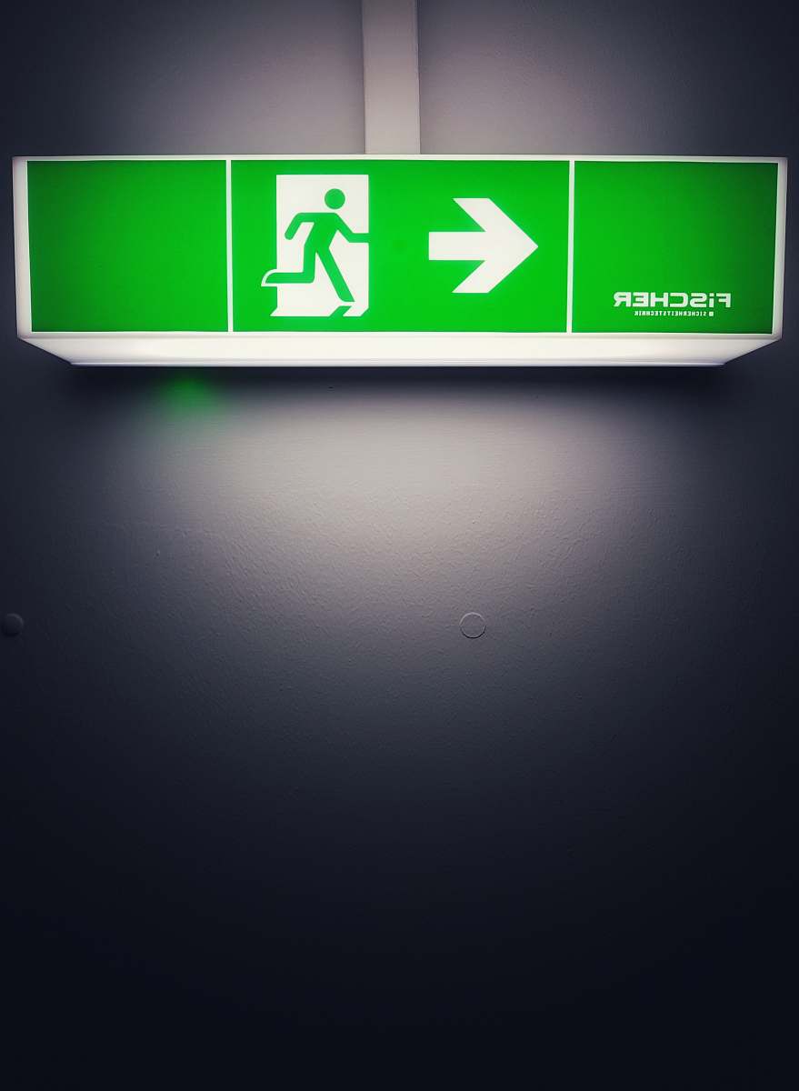arror green road signage on wall exit