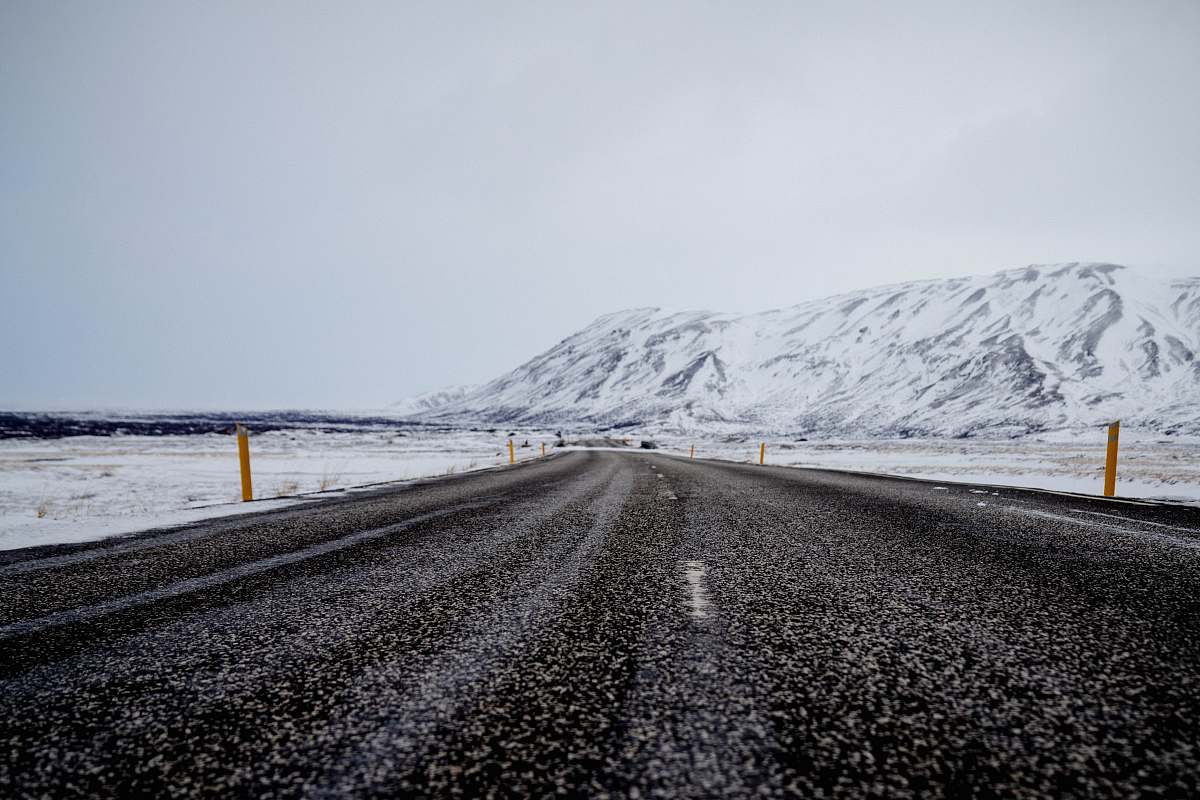 winter asphalt road near mountain filled with snow under cloudy sky road